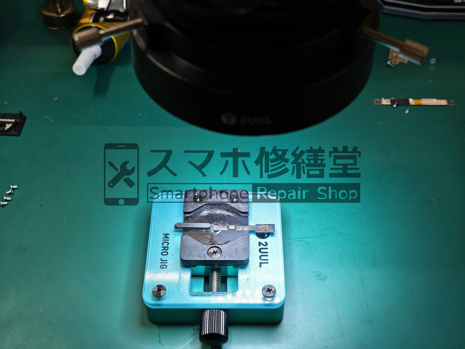 顕微鏡を使用して電源ボタンを修理する様子